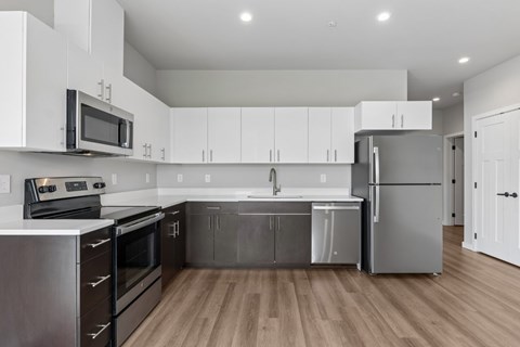 A modern kitchen with stainless steel appliances and wooden floors.
