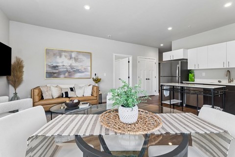 A modern living room with a glass table and white chairs.