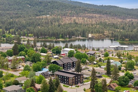 A small town with a large lake and a dam in the background.