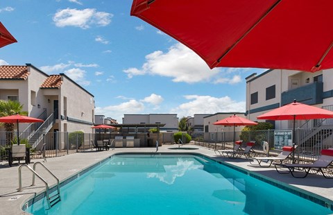 A swimming pool surrounded by red umbrellas and chairs.