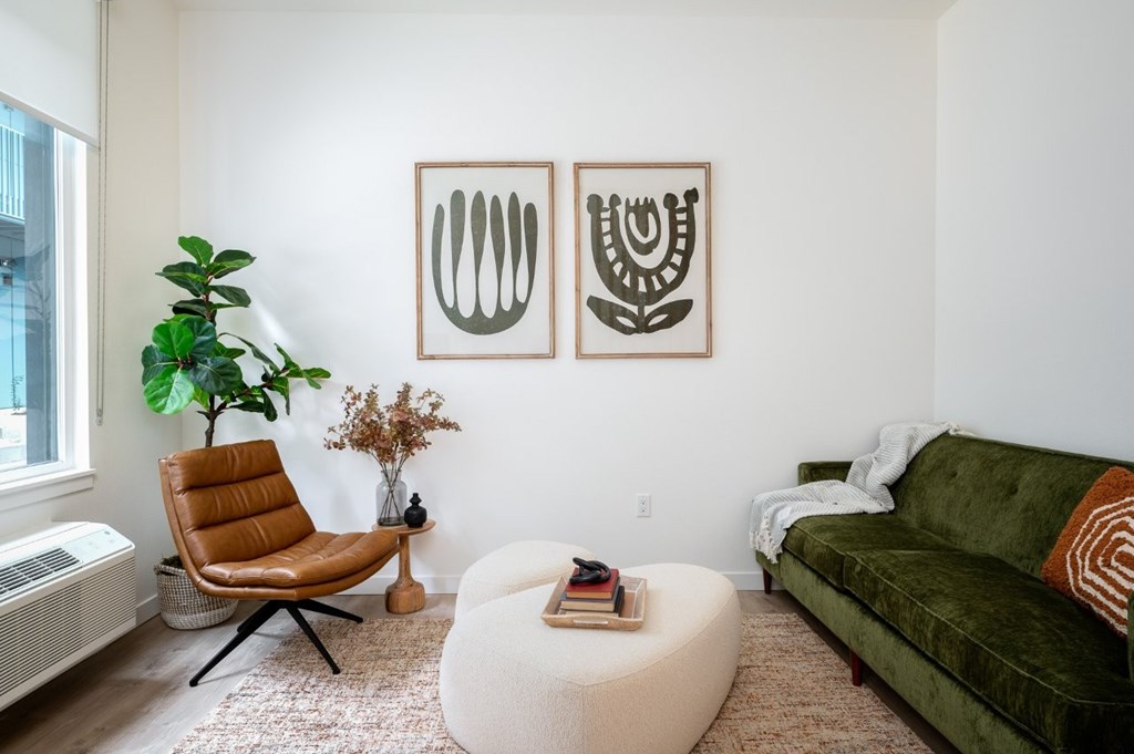 The Wes Gresham Oregon Apartments leather chair with white ottoman and a green couch. Art on wall
