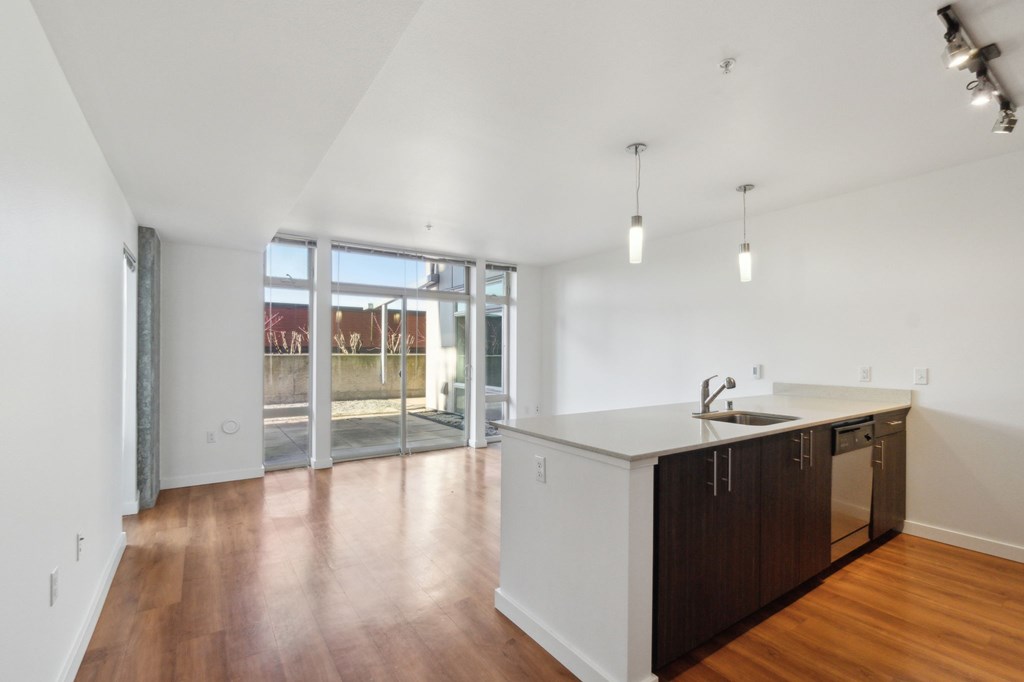 A kitchen with white walls and wooden floors.