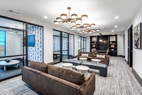 A modern living room with a brown sofa and a chandelier.