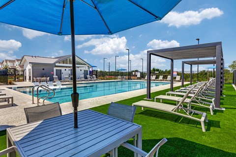 A poolside table with a blue umbrella over it.