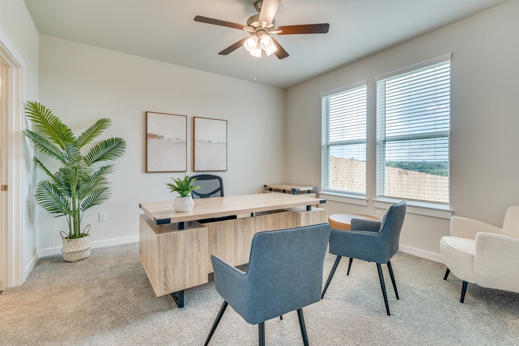an office with a desk and chairs and a ceiling fan