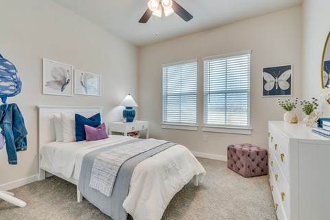 a bedroom with a bed and a dresser and a ceiling fan