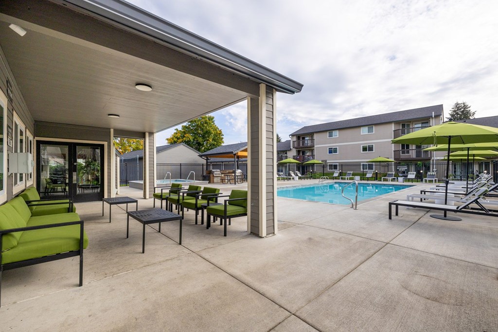 A patio with a pool and a green umbrella.
