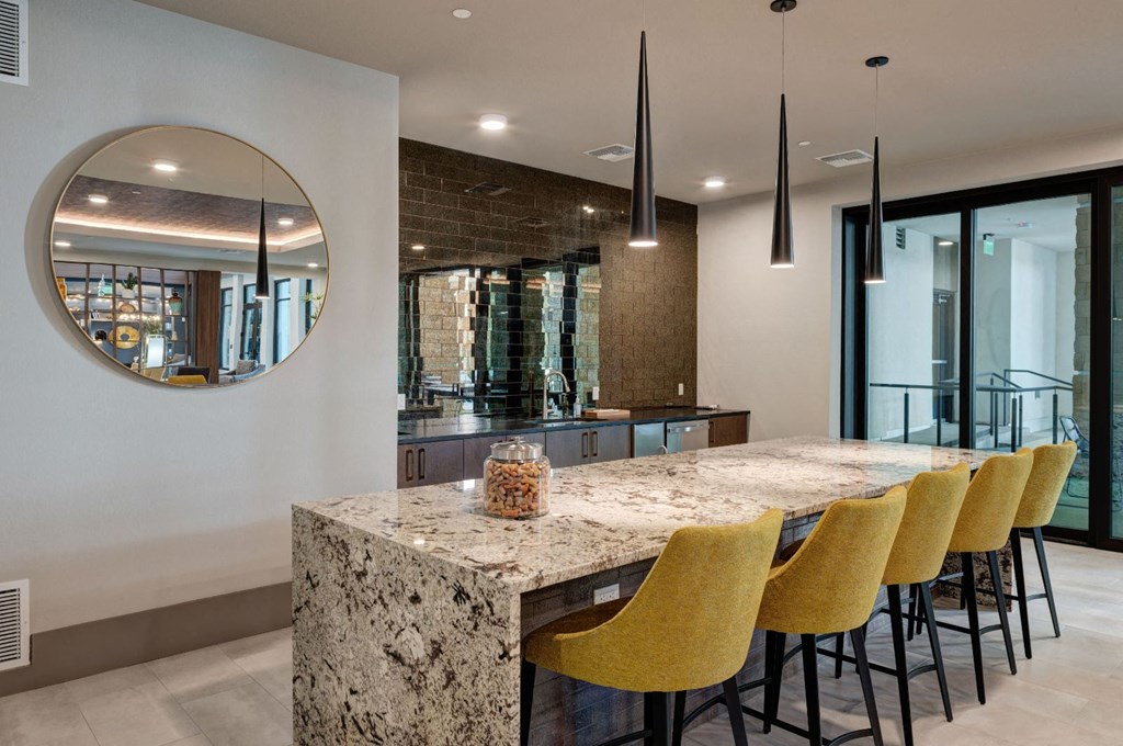 a kitchen with a marble counter top and yellow chairs