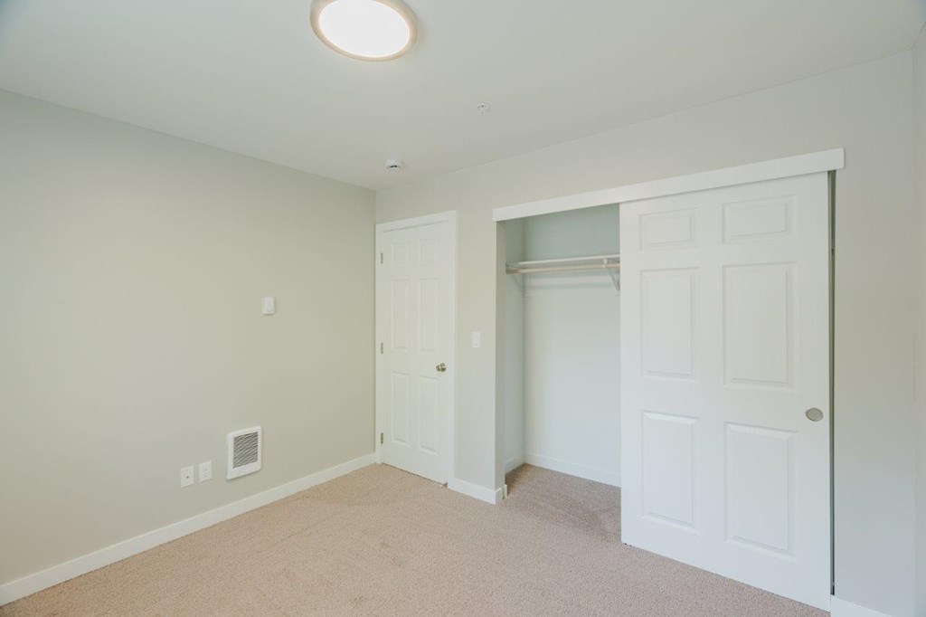A room with a white door and a carpeted floor.
