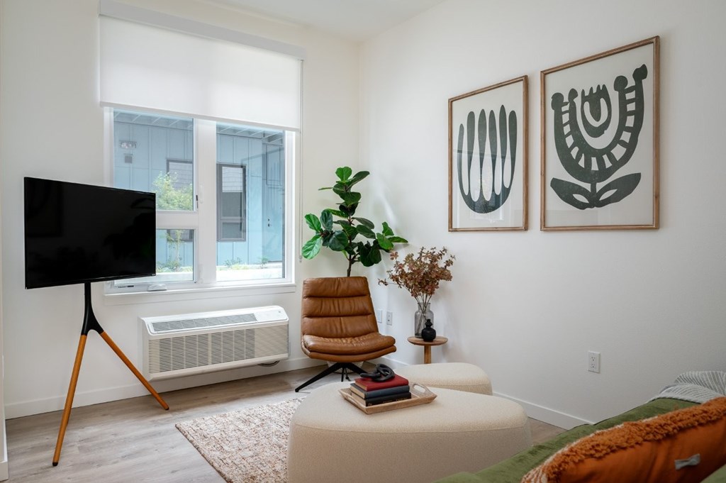 The Wes Gresham Oregon Apartments  leather chair with white ottoman and a green couch. Art on wall