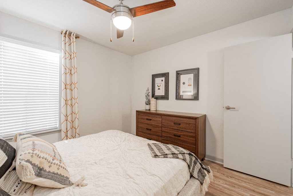 a bedroom with a bed and a dresser and a window