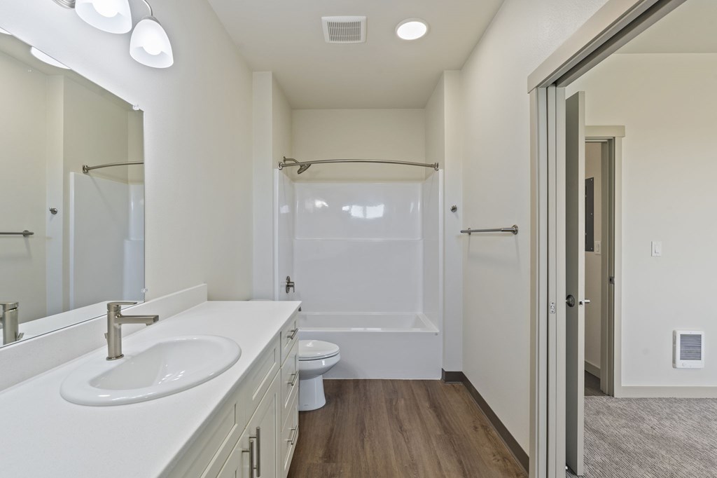 A white bathroom with a sink, toilet, and shower.