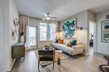 A living room with a white couch, a wooden coffee table, and a large painting on the wall.