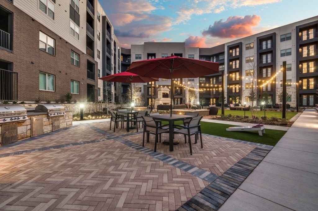 A patio with a table and chairs under a red umbrella.