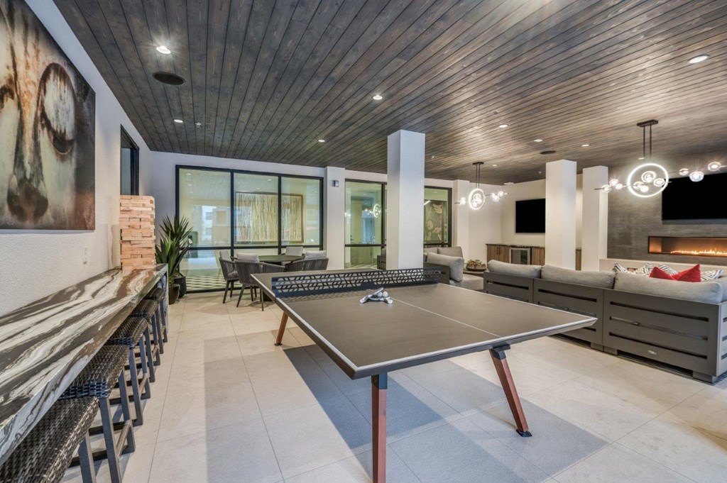 A ping pong table is in the middle of a room with a wooden ceiling.