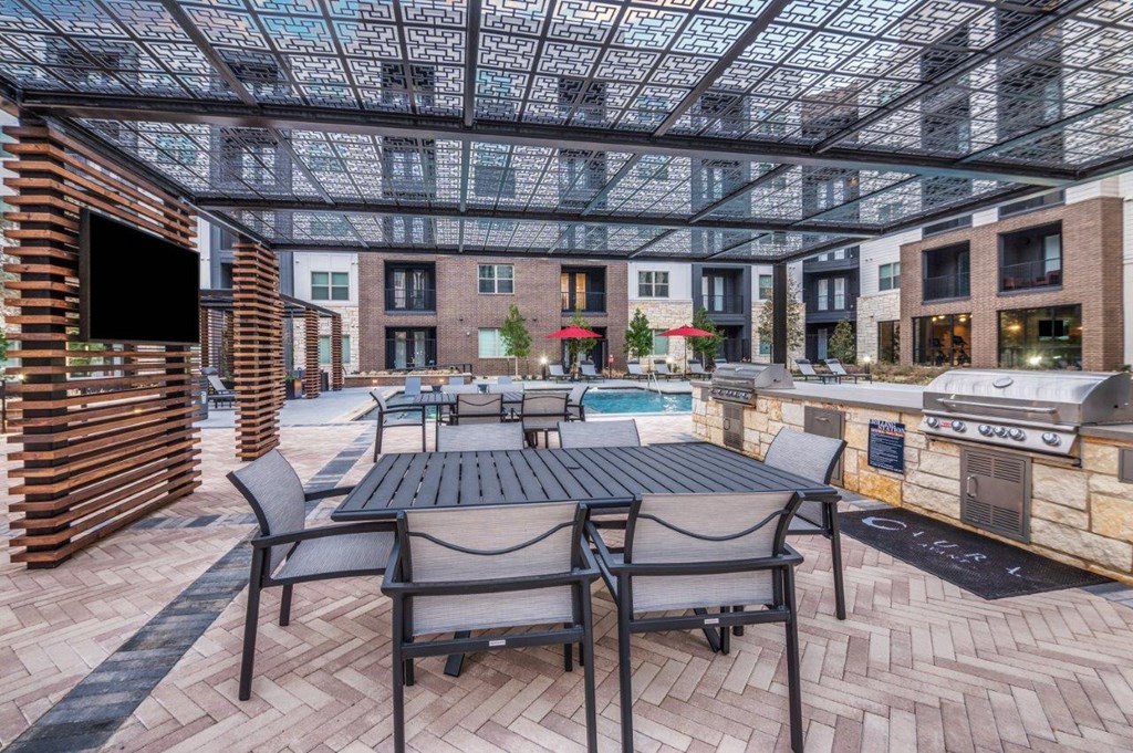 A patio with a table and chairs is surrounded by a brick wall and a glass ceiling.