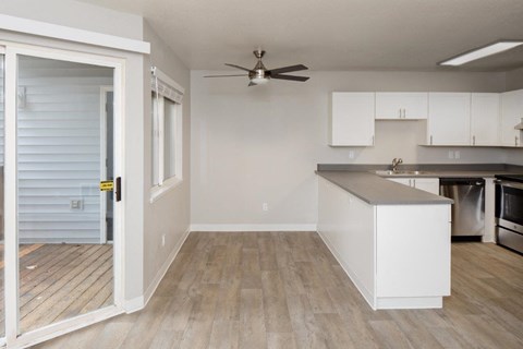 an empty kitchen and living room with a ceiling fan