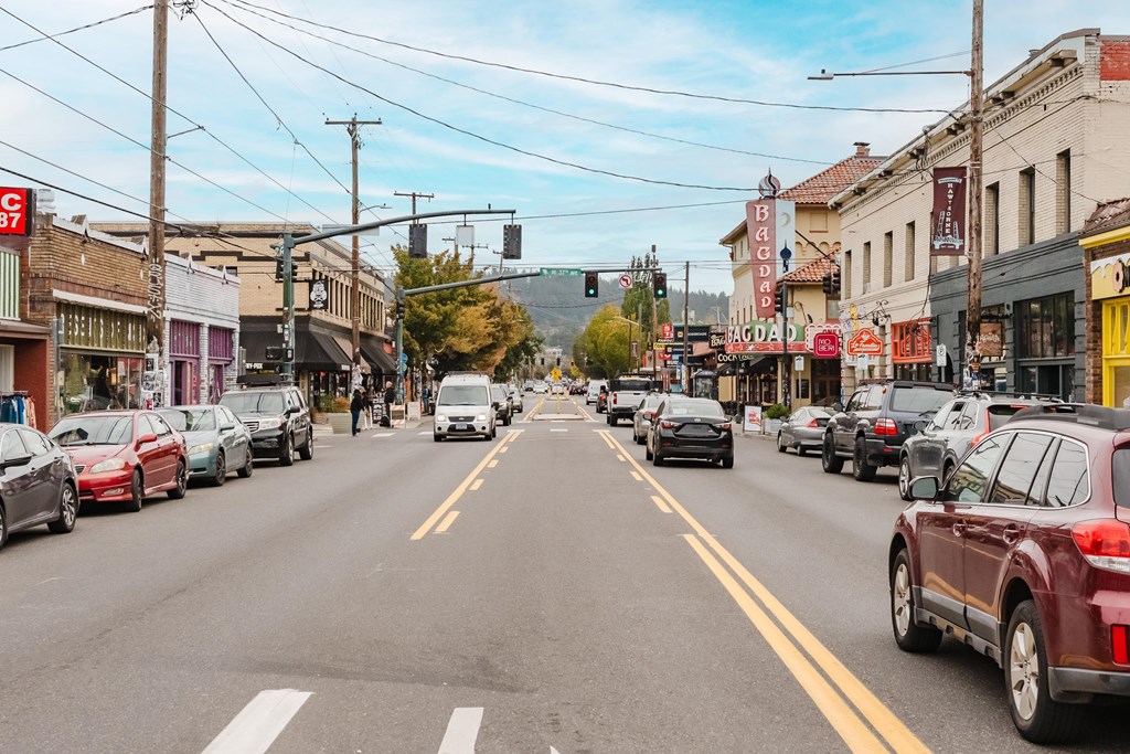 A street scene with cars parked on the side of the road and a few moving cars.