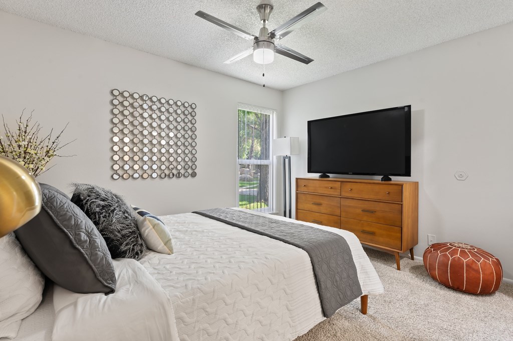 A bedroom with a bed, dresser, and television.