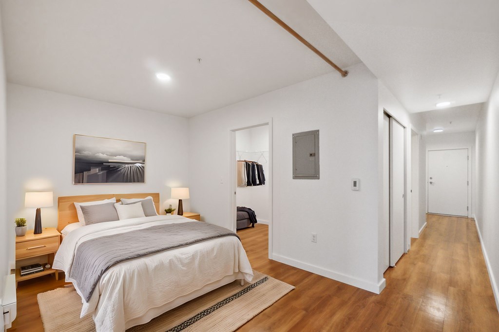 A bedroom with a large bed and a painting on the wall.