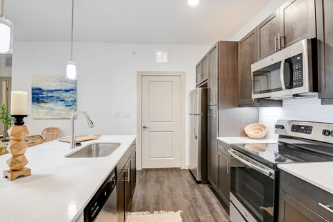 A modern kitchen with dark wood cabinets and stainless steel appliances.