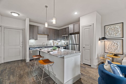 A modern kitchen with a bar stool and a blue sofa.