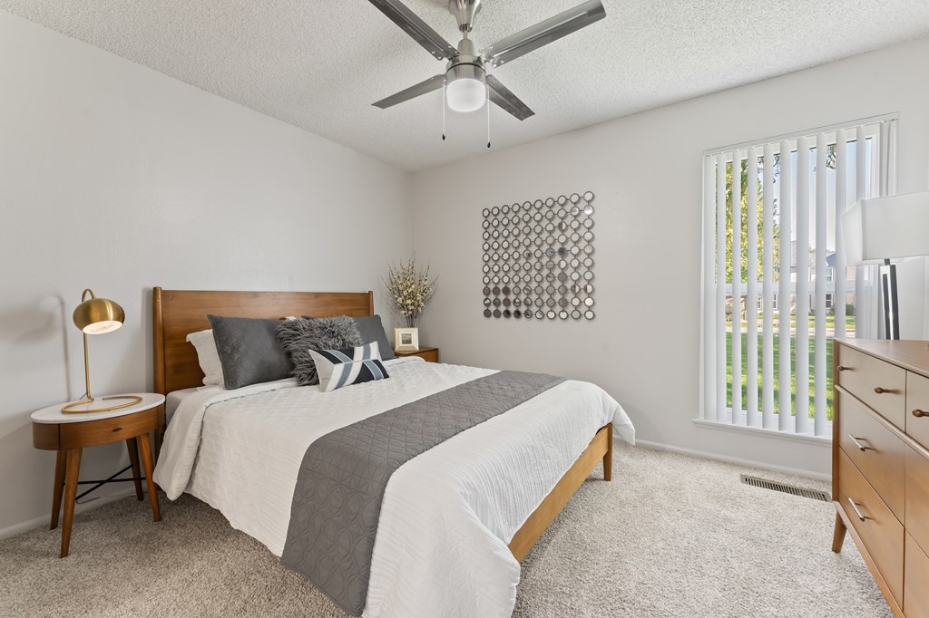 A bedroom with a bed, nightstand, and a ceiling fan.