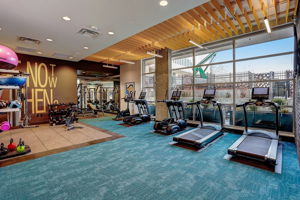 a gym with cardio equipment and a large window