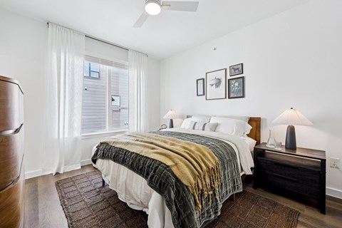 A bedroom with a bed, nightstand, and pictures on the wall.