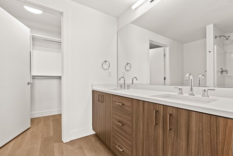 A bathroom with a white counter and wooden cabinets.