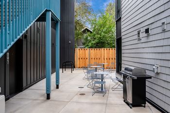 A patio with a table and chairs and a grill.