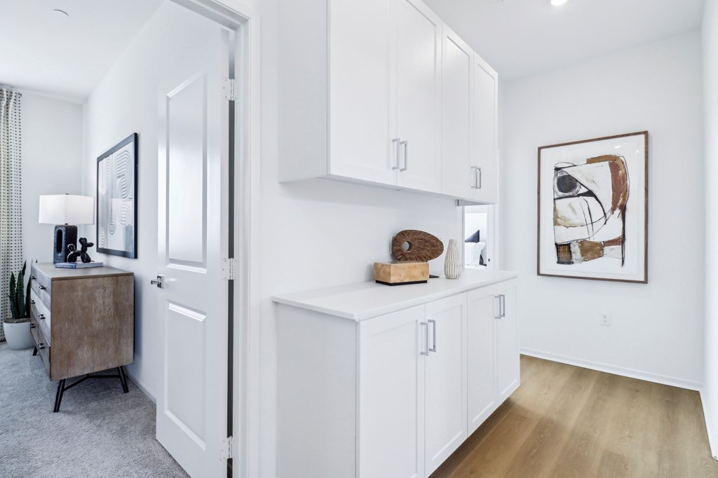 A white kitchen with a wooden floor and a painting on the wall.