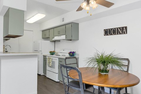 A kitchen with a table and chairs and a sign that says Cucina.