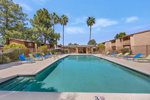 A swimming pool surrounded by palm trees and lounge chairs.