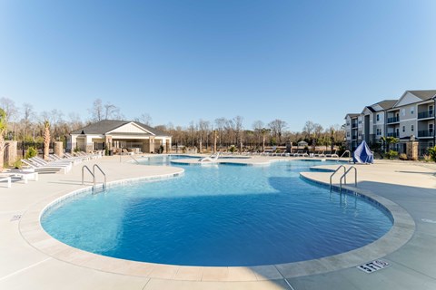 A large outdoor swimming pool with a slide and a building in the background.