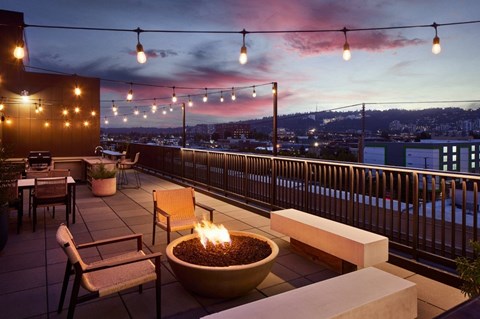 A patio with a fire pit and chairs.