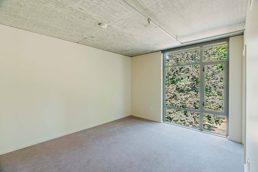 Empty room with a window overlooking a tree-filled landscape.