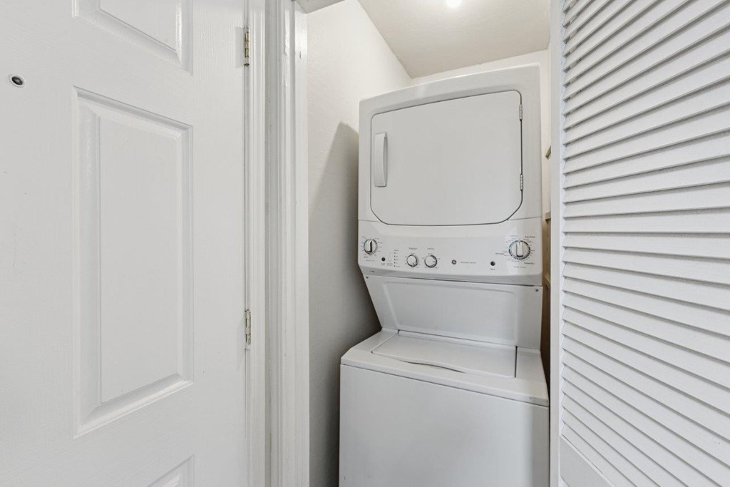 A white washing machine is in a small space between a door and a wall.