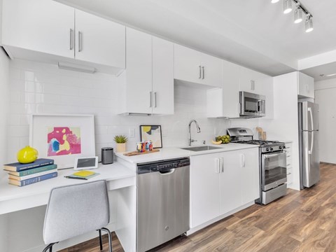 A modern kitchen with white cabinets and stainless steel appliances.
