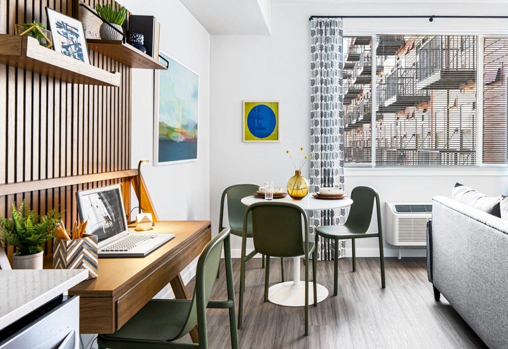 a living room with a table and chairs and a laptop