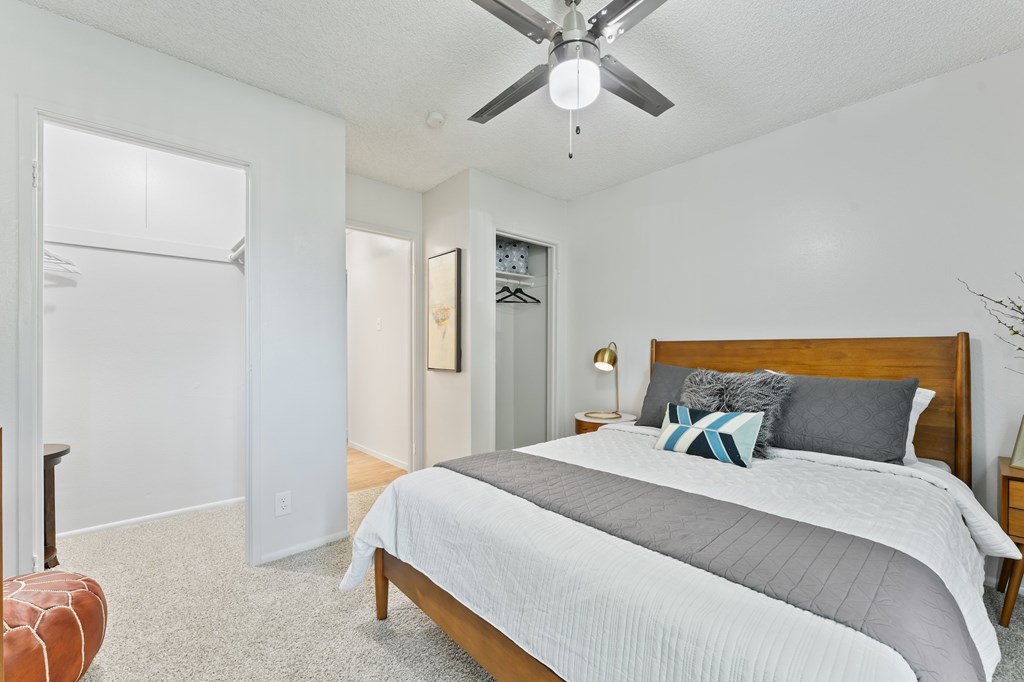 A bedroom with a bed, a ceiling fan, and a chair.