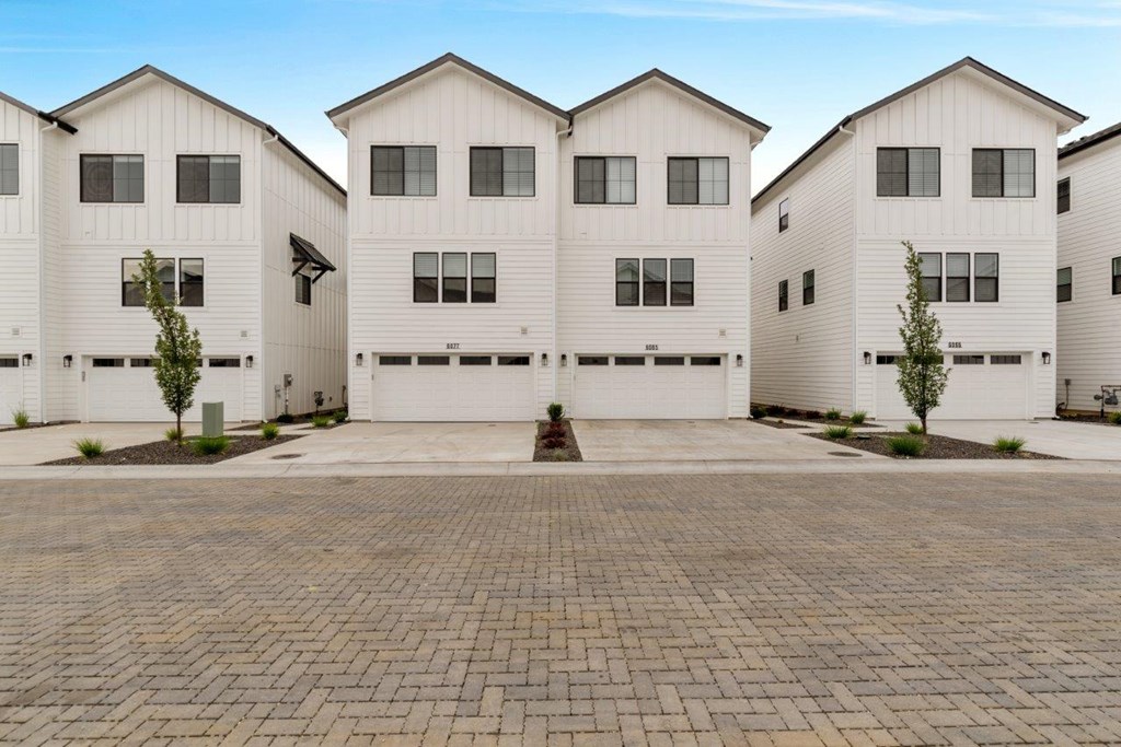 A row of white houses with a brick driveway in front.