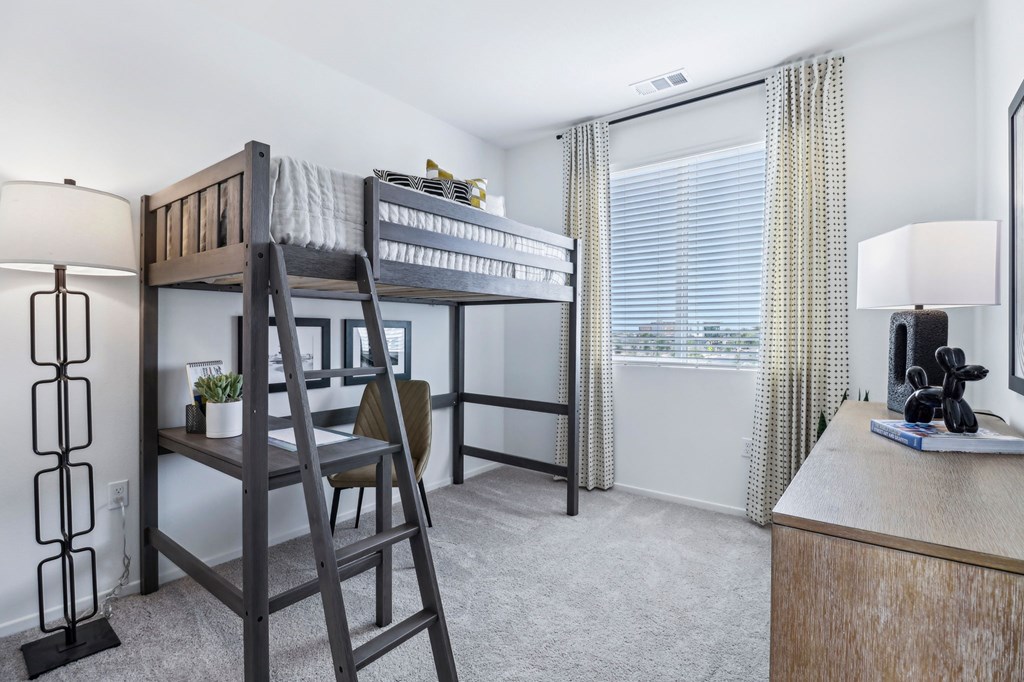 A room with a bunk bed and a desk.