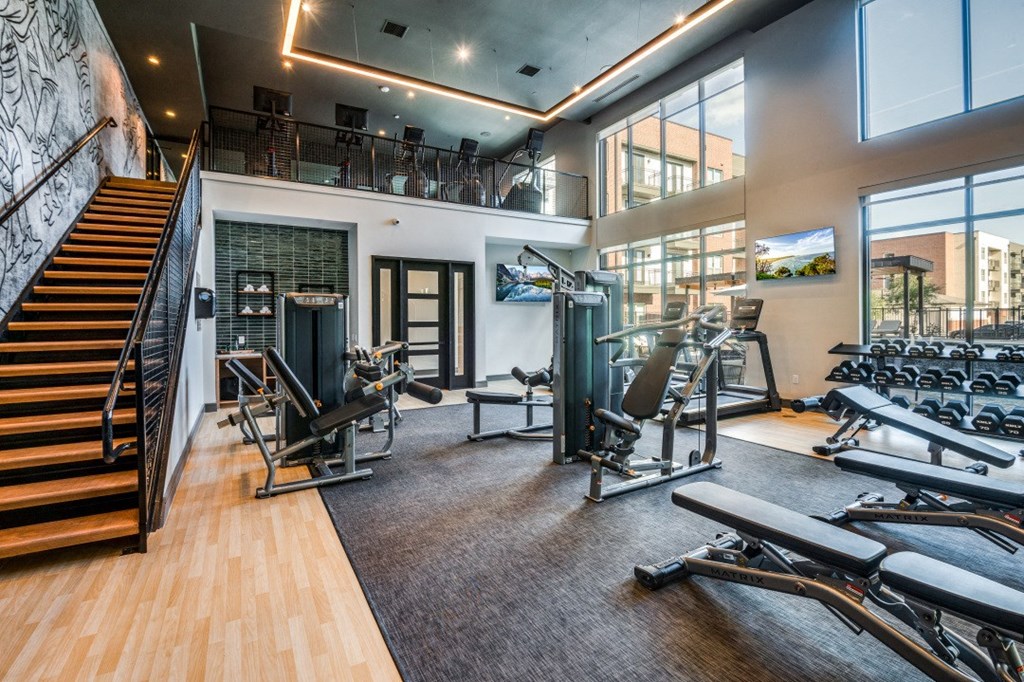 a gym with treadmills and other exercise equipment and a staircase
