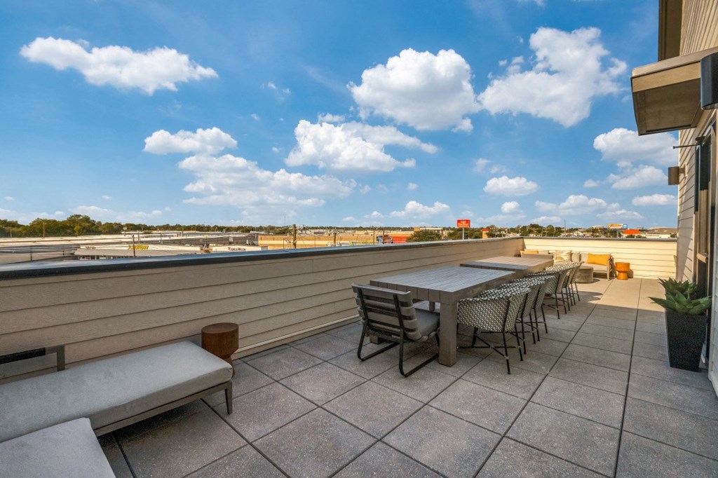 a rooftop patio with tables and chairs and a view of the city