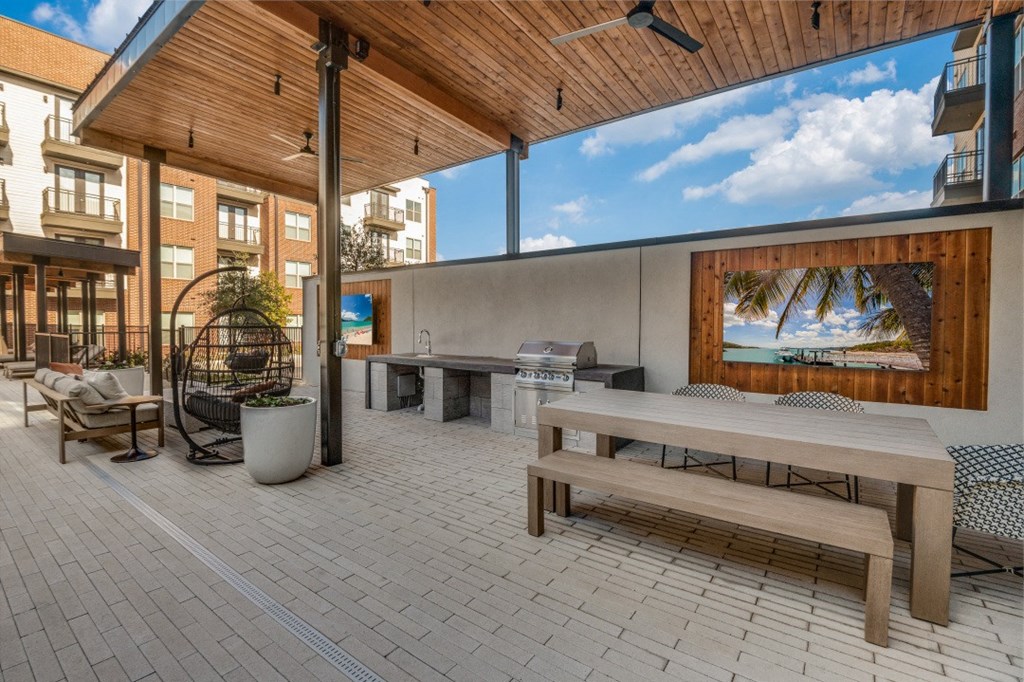 the outdoor patio has a picnic table and a grill and a bench