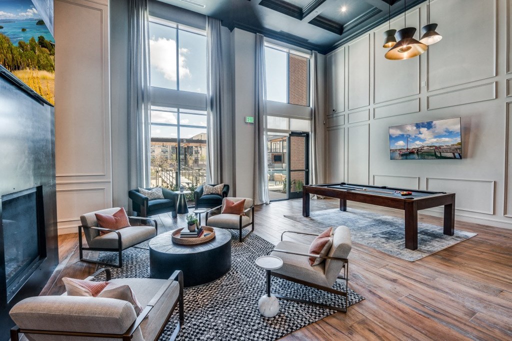 a living room with a pool table and large windows