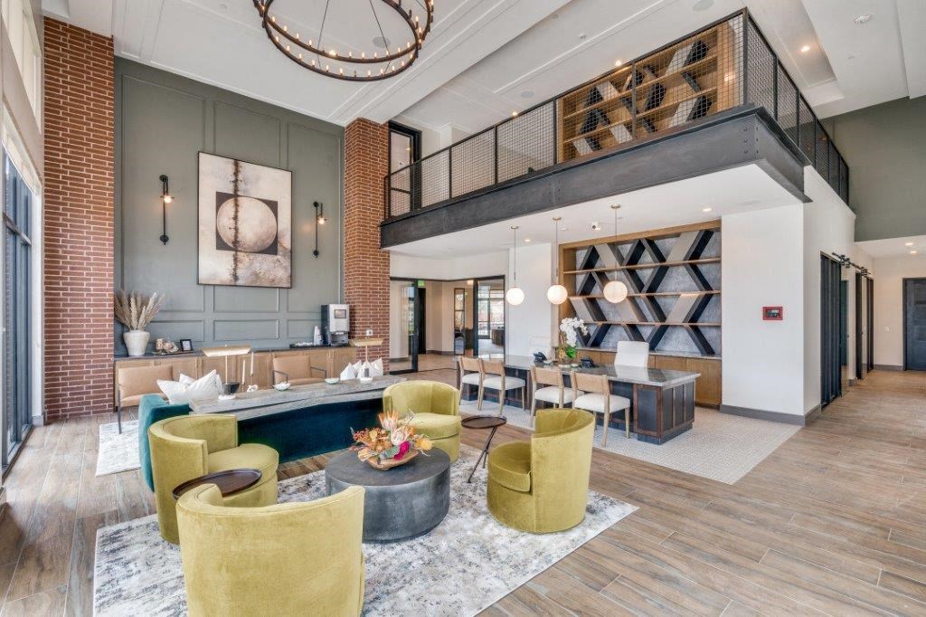 a lobby with a staircase and a lobby area with yellow chairs and a blue couch