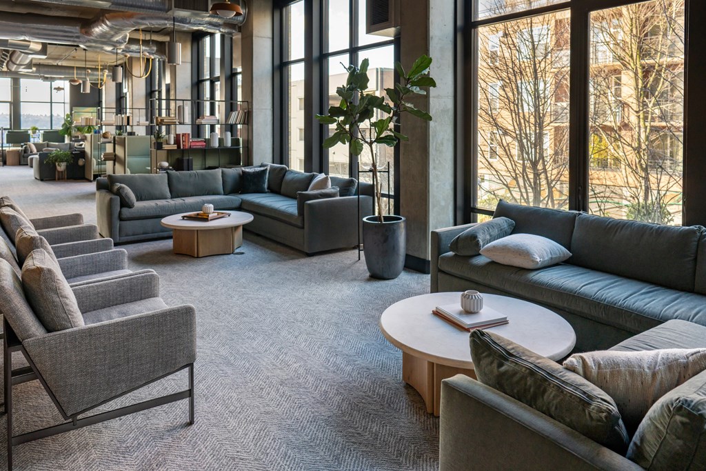 A living room with grey couches and a large window.