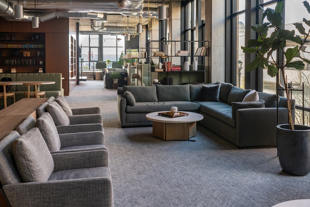 A modern office lounge with grey couches and a wooden table.